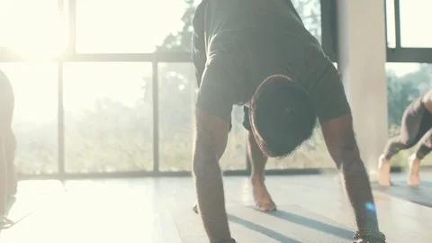 People practice yoga pose in sunny studio high key shot rapid slow motion Stock Footage