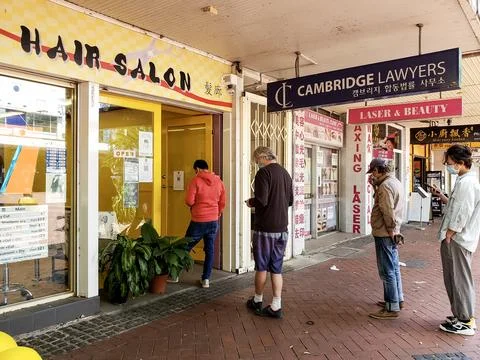 People practicing social distance queue outside a hair salon Stock Photos