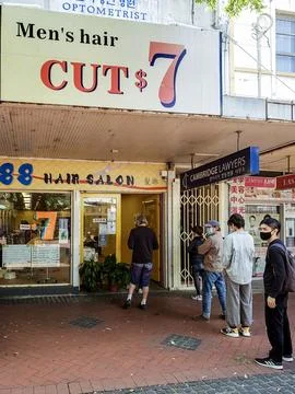 People practicing social distance queue outside a men's hair salon Foto stock