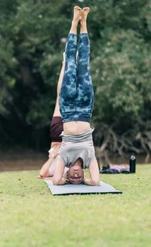 People practising yoga in a reverse position in a park Stock Photos