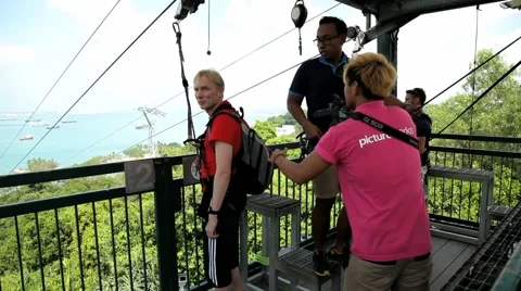 People prepare to start sliding with the zip line at Sentosa, Singapore. Stock Footage 61839137