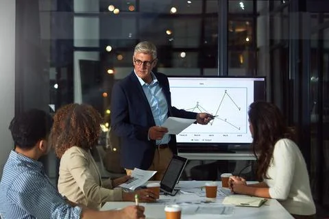 People, presentation and document in office at night with finance report, d.. Stock Photos