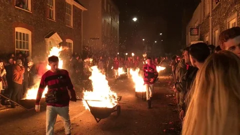 People pulling flaming wheelbarrows during Lewes Bonfire Stock Footage 114375459