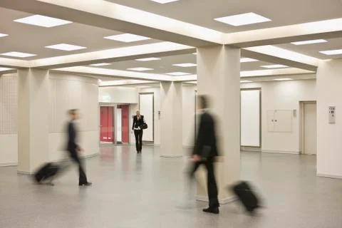 People pulling suitcases walking in different directions Stock Photos