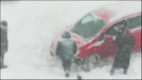 People push red car stuck deep snow during winter blizzard, struggle with Video stock 329214279