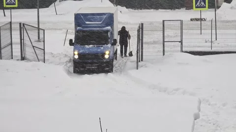 People pushing stuck blue delivery truck in deep snow during heavy winter Stock Footage 326750106