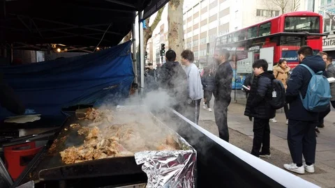 People queue for chicken cooking at a food market stall in London, UK Stock Footage 103794503