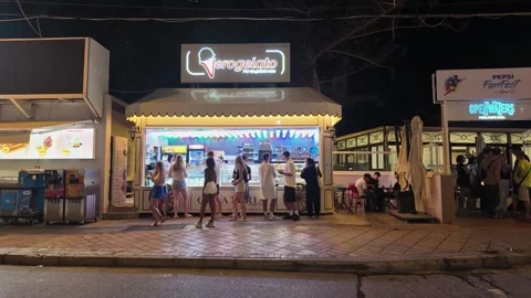 People queue in front of an ice cream stall on a warm summer night in 스톡 동영상 314358472