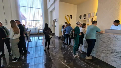 People queue at hotel reception desk in modern lobby with large windows Stock Footage 333024606