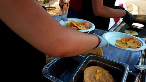 People in a queue, lifting tortillas and shells, on a plate, at a outdoor Stock Footage 116755121