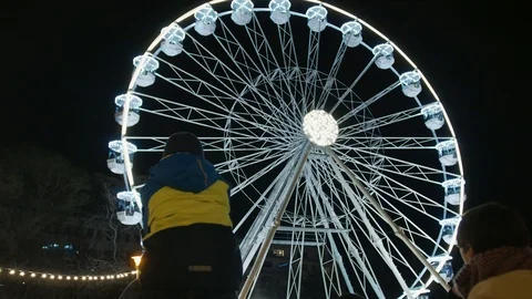 People in queue look at ferris wheel in night illumination Vídeos de archivo 99839398