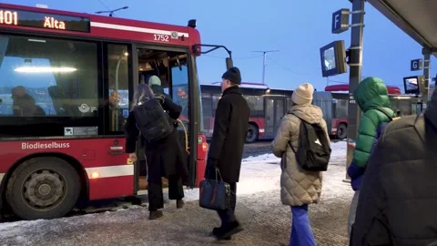 People queue respectfully at a bus stop in winter as they enter the vehicle - Video stock 338187130