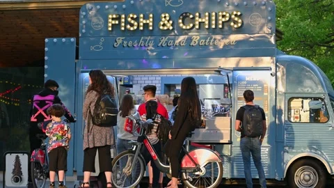 People queuing at a fish and chip van on South Bank with people walking past Stock Footage 159237181