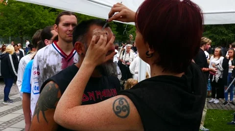 People queuing for make up artist to make wounds on their face for zombie walk Stock Footage 68703299