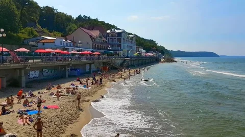 People relax and sunbathing at Baltic Sea shore at sunny summer day Stock Footage