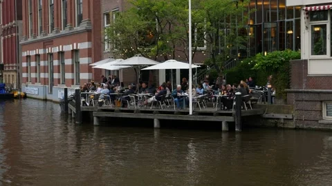 People rest in cafe at evening time, cozy open terrace at waterside Stock Footage 130220279