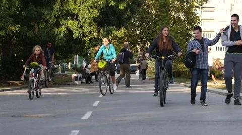 People ride bicycles in a park public place healthy lifestyle slow motion Stock Footage