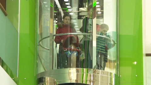 People ride in a transparent elevator in a mall. people are moving. Stock Footage 113566745