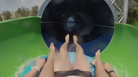 People rides by green slide in water park Stock Footage