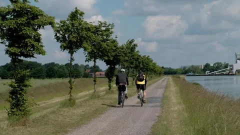 People riding bicycles on a path along a scenic water canal Video stock 337298954