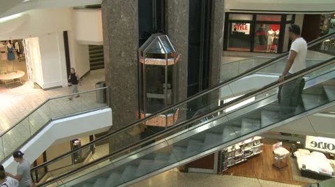 People riding down escalator next to elevators within mall (1 of 2) Stock Footage 32326997
