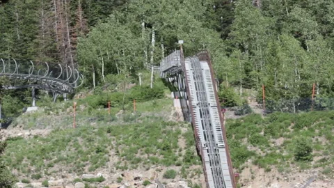 People riding a mountain rollercoaster in a windy day going into a forest Stock-Footage 100866166
