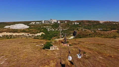 People riding a zip line over a landscape with greenery and buildings Stock Footage 341327341