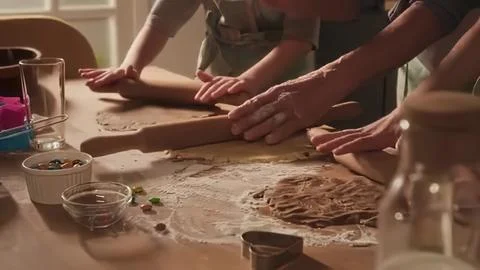 People rolling dough in a cozy kitchen for baking Stock Photos