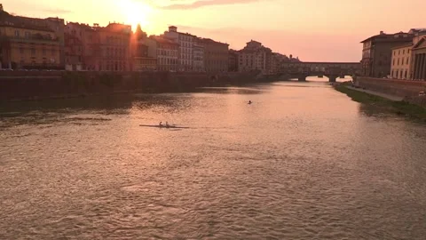 People rowing on the Arno River by the Ponte Vecchio at sunset Stock Footage 161019422