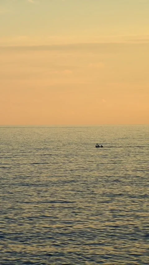 People rowing small boat across calm ocean at sunset Stock-Footage 345080037