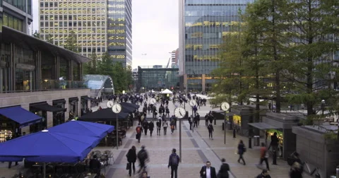 People rushing from work with several clocks in the Docklands, London Stock Footage 68579150