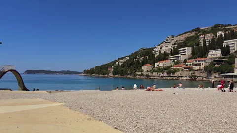 People at the sandy pebbles Uvala Lapad Beach, Dubrovnik, Croatia, 4k Video stock 276365741