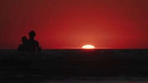 People in the sea looking at sunset Stockbeeldmateriaal 237758277