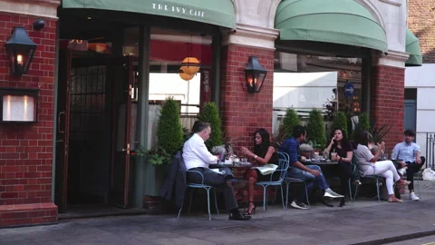 People seating dining and drinking coffee outdoor restaurant in London Stock Footage 146291064