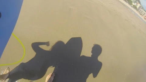 People shadows walking while carrying a bodyboard road to the sea Stock Footage 104306196