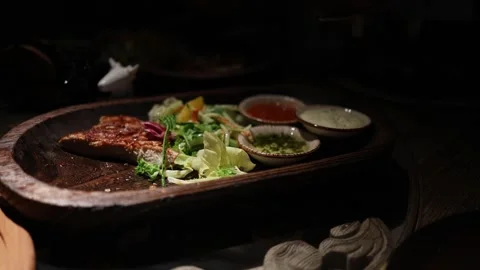 People share and cut steak at a lively dinner table with assorted dishes Stock Footage 344744583