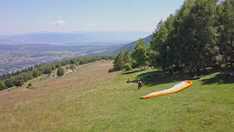 People on side of mountain prepare to go paragliding. Person with large Video stock 253617167