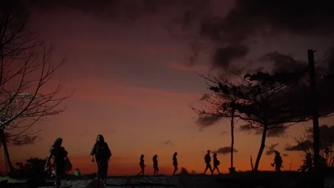 People silhouetted walking against a dramatic sunset sky Видео 339315694
