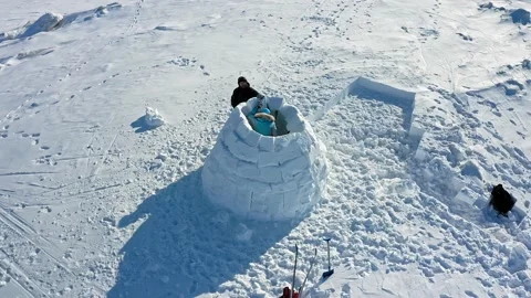 People silhouettes build igloo with large snow bricks aerial Stock Footage 131463671