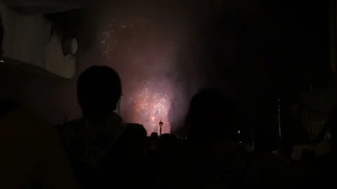 People silhouettes watching exploding fireworks on a dark night at the city. Stockbeeldmateriaal 104067731