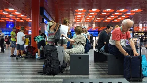 People sit on a bench in a train station building - view from the side Vídeos de archivo 92837272