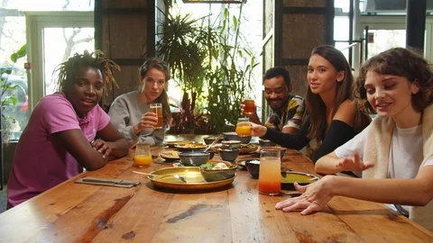 People sit in a cafe, they talk at the camera and offer food and drink Stock Footage 121941736