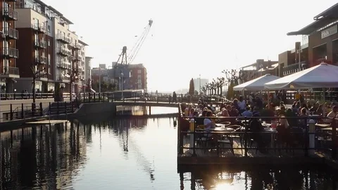 People sit outside a cafe at the water's edge in Gunwharf Quays, portsmouth Stock Footage 105548601