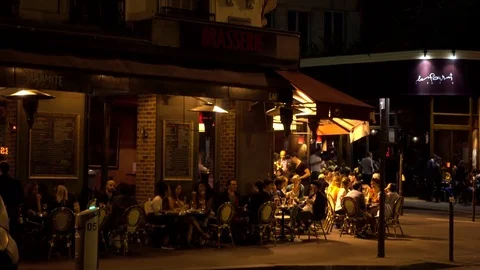 People sit relax by the tables of cozy street cafe Montmartre Paris Night Stock Footage