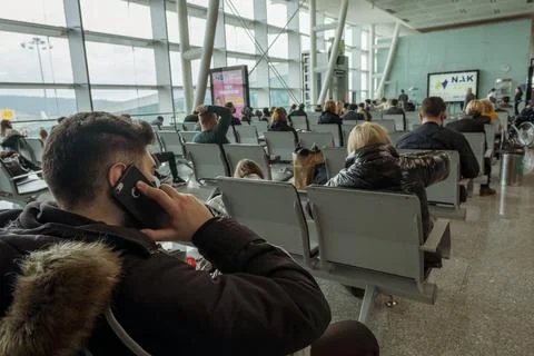 People sitting on airport seats and one man talking to phone in airport Stock Photos