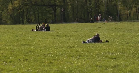 People sitting and lying on grass in park 스톡 동영상 332511679