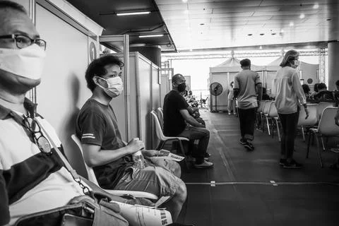 People sitting and waiting in queue for vaccinations to against covid 19 Stockfoto's