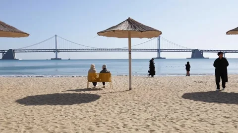 People Sitting on Bench Between Beach Umbrellas in Busan South Korea Stock Footage 327581492
