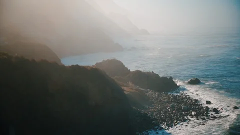People sitting on cliffs watching the waves crash against the rocks Stock Footage 102417189