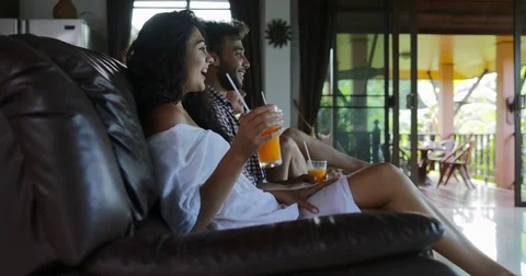 People Sitting On Coach Watch Tv In Living Room Drink Orange Juice, Young Man Stock Footage